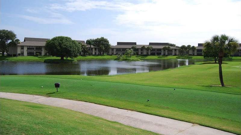 003 - A Vista Plantation home overlooking a tranquil pond with a lush green lawn in the foreground under a clear blue sky_